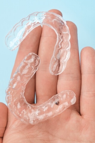 Hand holding two clear aligners