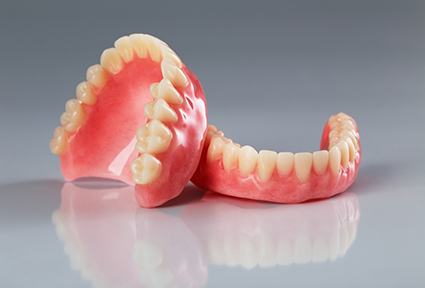 Set of full dentures on a reflective background