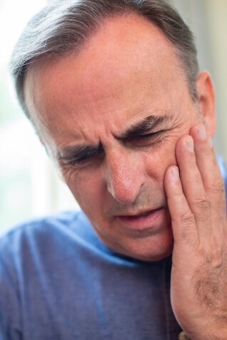 Man touching his face in pain