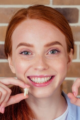 Smiling woman holding an extracted tooth