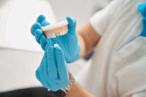 Dentist removing a dental crown from a model set of teeth